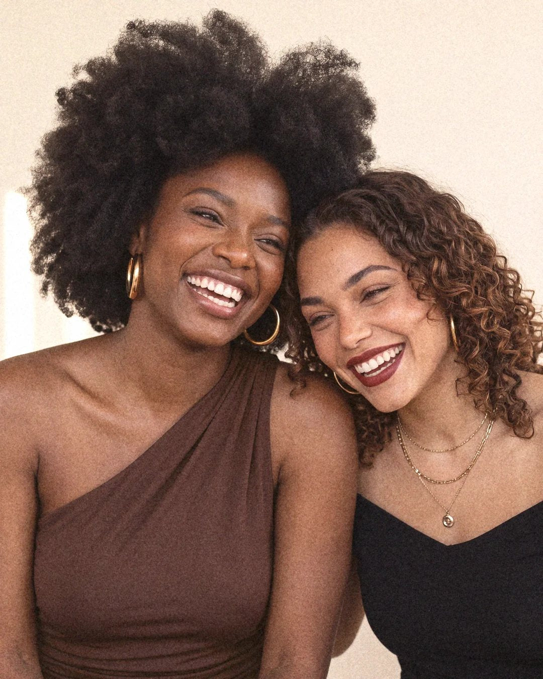 Two women laughing together, heads touching.